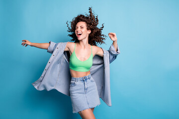 Photo of cute charming young lady smiling eyes closed hands raised up open mouth dance beach party wind blow hair wear denim mini skirt shirt green crop top isolated blue color background