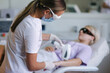 © Aleksandr - Beautician in medical mask doing epilation on beautiful woman's hand in medical center. Female receiving laser light hair removal treatment for hairless smooth skin at cosmetology salon