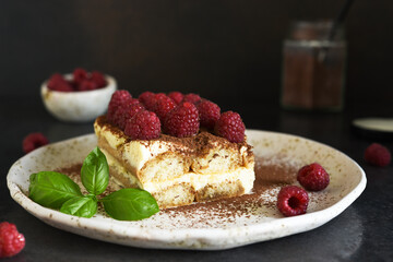 Wall Mural - Tiramisu with raspberries on a dark concrete background. The classic Italian dessert is tiramisu.