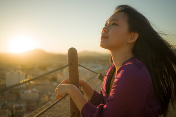 young happy and beautiful Asian Japanese woman outdoors at viewpoint balcony enjoying sunset view of Spain town during Europe holiday travel feeling free