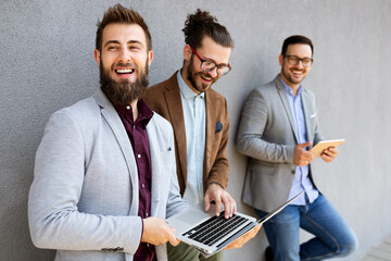 Cheerful happy businessmen using laptop at the meeting outdoor