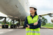 Asian woman engineer maintenance airplane arm crossed and holding wrench in front airplane from repairs, fixes, modernization and renovation in airport..