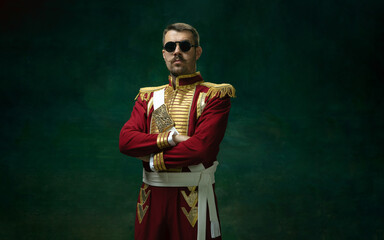 wearing stylish eyewear. young man in suit as nicholas ii isolated on dark green background. retro s