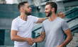 © My Ocean studio - Two happy excited handsome bearded best friends in casual clothes are handshaking, hugging while standing outdoor.