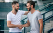 © My Ocean studio - Two happy excited handsome bearded best friends in casual clothes are handshaking, hugging while standing outdoor.
