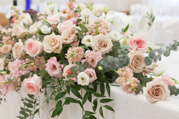 Wall Mural - A beautiful floral arrangement in light colors is on the table with a white tablecloth.