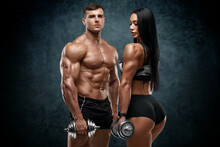 Sporty Couple Workout With Dumbbells. Muscular Man And Woman Showing Muscles