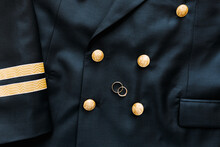 Top View Of Two Gold Wedding Rings On A Black Mens Blazer With Buttons With A Two-headed Eagle.