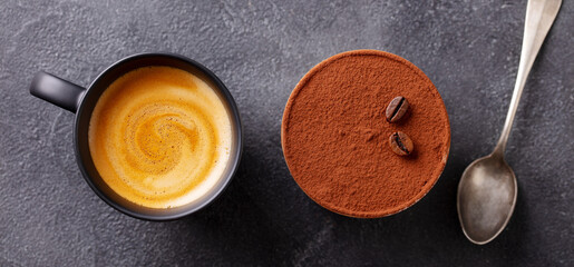 Tiramisu dessert with cup of coffee. Dark grey background. Close up. Top view.