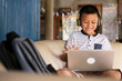 © Chansom Pantip - Online remote learning, distance education and homeschooling concepts. School kid Asian preteen boy in headphone using laptop computer on couch in rustic rural home during COVID-19 pandemic.
