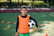 © gorynvd - Handsome tired boy in football uniform with ball after training on the stadium in the urban green park on summer day.