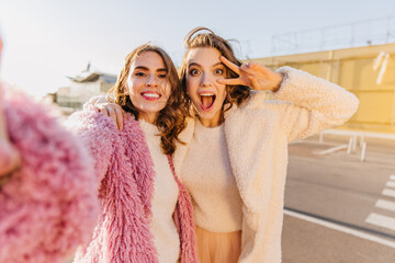 Sticker - Carefree ladies funny posing on the street in autumn. Emotional girls fooling around after shopping.