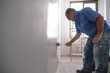 © Ladanifer - Real senior house painter painting a grey wall with a paint roller. Real dirty worker. House painter profession concept.