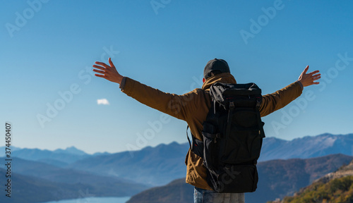 Cuadros en Lienzo A traveler with a backpack stands on the top of the mountain and holds his hands