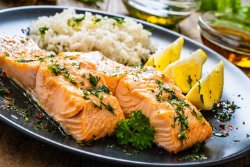 Roasted salmon steaks with lemon, basmati rice and lemon served on wooden table
