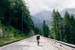 © BublikHaus - Professional road cyclist on fast and light carbon bicycle descends mountain road in Alps Dolomites. Fit and athletic man on recreational ride trip or training camp, enjoy time outdoors on bike
