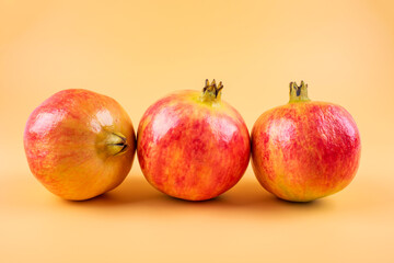 Three fresh pomegranate fruits on yellow background