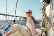 © Artem Varnitsin - Happy mature woman wearing sunglasses on a sailboat and looking at camera. Senior female sitting on yacht deck and enjoying the voyage.
