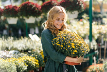 Positive Fair-haired Girl Holding Yellow Flowers. Portrait Of Smiling Romantic Lady Enjoying Gardening In Warm Day