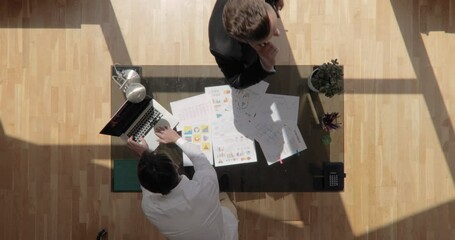 Top view shot of two business men are on the phone and working with laptop at conference table with floating sun shot in 4k