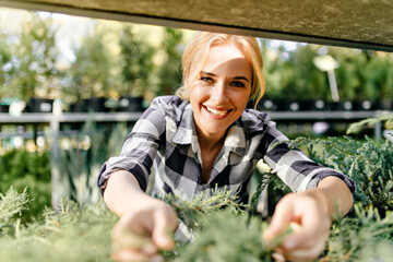 Wall Mural - Closeup portrait of girl with bright green eyes of incredible beauty. Sweet lady reaches for bush on shelf