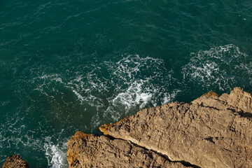 Wall Mural - Clear amazing azure colour sea water with rocks in Spain. View of sea waves and fantastic Rocky coast. Stone rock close up in the sea water. Rock and sea.