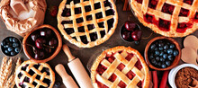 Baking Scene With A Variety Of Homemade Fruit Pies. Top View Over A Wood Banner Background.