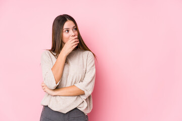 Wall Mural - Young caucasian woman posing isolated thoughtful looking to a copy space covering mouth with hand.