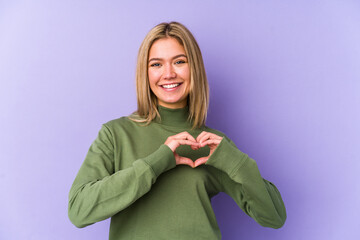 Poster - Young blonde caucasian woman isolated smiling and showing a heart shape with hands.