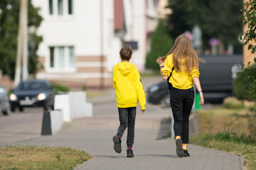  boy and girl in yellow clothes are walking through the city