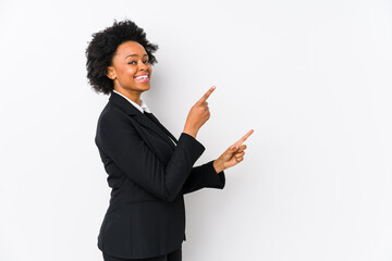 Wall Mural - Middle aged african american business  woman against a white background isolated excited pointing with forefingers away.