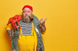 © wayhome.studio  - Shocked plump sailor shows direction to sea, points thumb on right, demonstrates copy space for your advertising content, promots fishing gears, poses with pipe in mouth, octopus on shoulder
