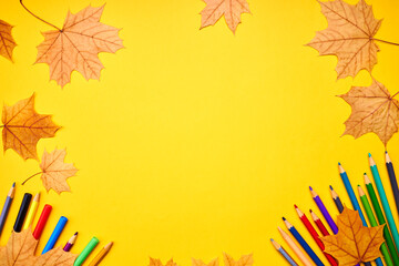Wall Mural - education and stationery concept. above view for yellow desk. decorated fall leaves and color pencils, markers and other tools. empty space for design