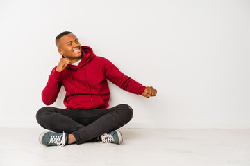 Young latin man sitting on the floor isolated dancing and having fun.