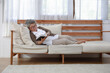 © kamonrat - Senior woman reading a book alone on sofa in a retirement home.