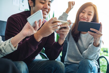A group of young people having fun and celebrating while watching and playing games on mobile phone together