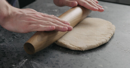 man rolling dough on concretre countertop