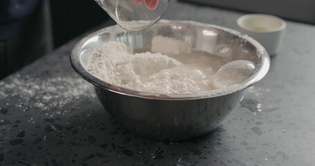 Wall Mural - wet ingredients into flour in steel bowl on concrete countertop