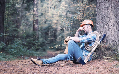 Poster - Male lumberjack in the forest. A professional woodcutter inspects trees for felling.