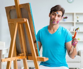 Young funny artist working on new painting in his studio