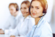 © rogerphoto - Call center operators. Focus on beautiful business woman using headset in sunny office