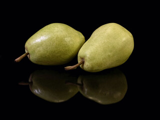 Green ripe pear on a black background. Bera pear variety, large fruits. Autumn fruits.