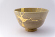 Kintsugi beige tea ceremony chawan bowl. Gold cracks restoration on old Japanese pottery restored with the antique Kintsugi restoration technique. The beauty of imperfections. 