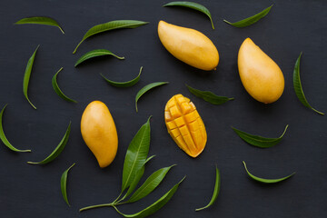 Sticker - Flat lay of Mango tropical fruit with green leaf on black wood background