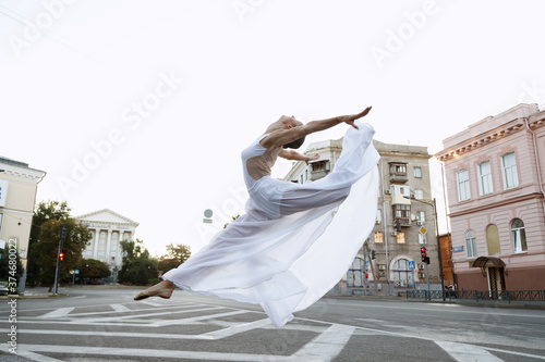 Girl dancer in white dress jumps in town Poster Mural XXL