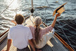 © Artem Varnitsin - Back view of a happy mature woman waving her straw hat on a yacht. Senior couple enjoying a vacation on a sail boat.