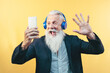 © Alessandro Biascioli - Happy senior man taking selfie while listening music with headphones - Hipster beard male having fun using mobile smartphone playlist apps - technology and elderly lifestyle people concept