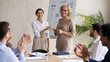 © fizkes - Smiling middle aged 60s female company leader shaking hands with happy young arabic colleague, praising for good work or thanking for good job done at briefing meeting with diverse employees.