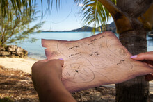 Hands Holding A Vintage Treasure Map On A Tropical Island