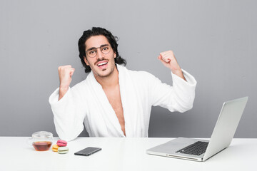 Wall Mural - Young handsome man working after a shower raising fist after a victory, winner concept.